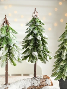 Close-up of mini snowy Christmas trees with artificial pine needles and winter snow texture