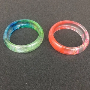 Dettaglio di bracciali in resina fai-da-te con glitter e fiori secchi, finitura lucida