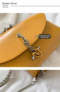 Detail showing smooth yellow faux leather bag with rhinestone chain and heart charm