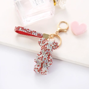 Close-up of a sparkling rhinestone bear keychain with red glitter hand strap for bag decor