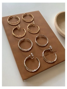 Goldene und silberne Doppel-Creolen als Set mit Clip-on und Stecker auf Lederunterlage