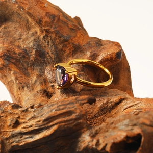 Detail view of 18k gold heart-shaped purple zircon ring on a natural wood base