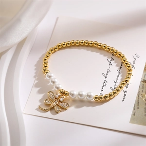 Macro shot of elegant dragonfly pendant pearl bracelet with golden beads on white silk