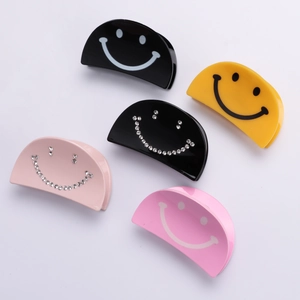 Set of five smile face acrylic hair clips in yellow, pink, and black with rhinestones