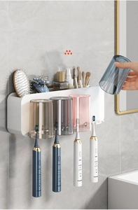 Detail view of wall-mounted organizer with four colorful cups and electric toothbrush holders