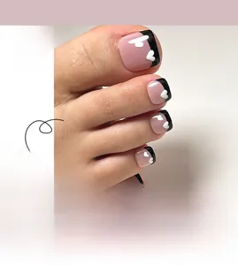 Close-up of pink French pedicure press-on nails with black tips and white heart details