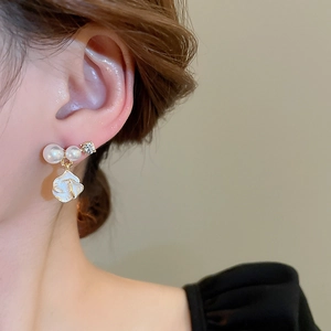 Gros plan de boucles d'oreilles fleur dorée avec perles et diamants sur modèle