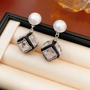 Detailed view of pearl earrings with zircon cube pendant in a luxury jewelry gift box