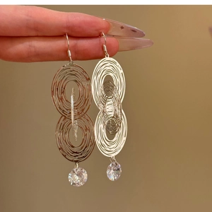 Silver hollow concentric oval earrings with sparkling cubic zirconia on a warm background