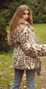 Outdoor close-up of a leopard print faux fur coat with a waist belt in natural light
