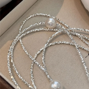 Detailed close-up of textured silver beads and white pearls on a minimalist necklace