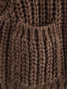 Close-up of brown chunky knit fabric texture showing weave details and pocket seam