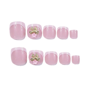 Glossy nude pink square press-on toenails with French tips and 3D gold bow charms