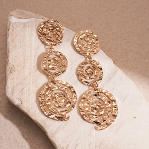 Détail de boucles d'oreilles pendantes spirales dorées avec texture martelée