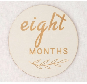 Détail d'un disque de naissance en bois avec gravure huit mois et motif de feuille