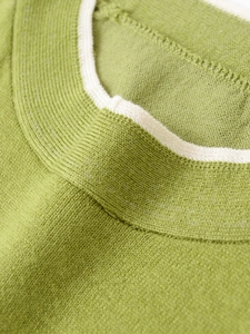 Detail of green knit sweater neckline with cream contrast trim and soft texture