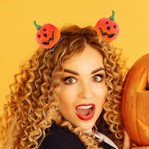 Set of two orange Halloween pumpkin hair clips with smiling faces on a yellow background