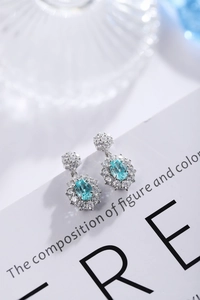Macro detail of silver drop earrings with oval light blue gemstone and halo stones