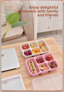 Detail of wheat straw bento boxes with multiple compartments and clear lids on a wooden table