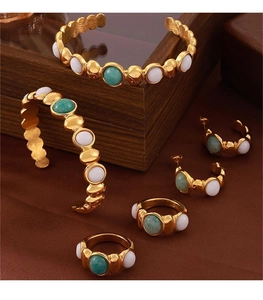 Gold-plated jewelry set with oval green stones and white gems on dark velvet