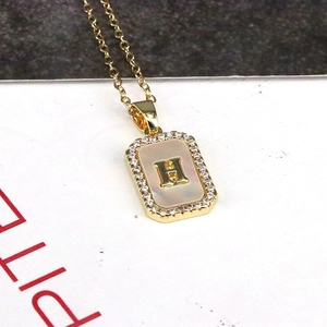 Macro shot of 18K gold rectangular necklace pendant with shell inlay and zircon H letter
