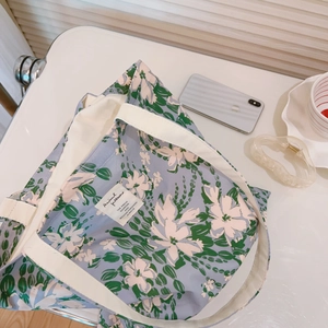 Detail of floral tote bag showing green leaves on purple canvas with cotton handle