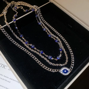 Close-up of silver layered evil eye necklace with blue rhinestones in a black velvet box