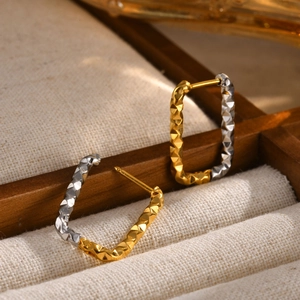 Macro shot of gold and silver two-tone square hoop earrings with diamond-patterned facets