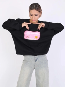 Detailaufnahme des schwarzen Oversized-Sweatshirts mit pinkem Print und lockerer Passform