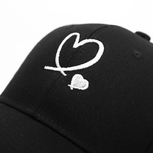 Close-up of double heart embroidery on black cotton twill baseball cap fabric texture