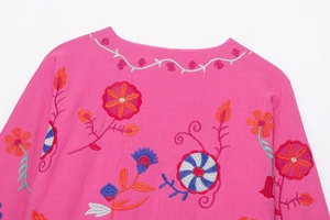 Macro detail of colorful floral embroidery on vibrant pink cotton linen fabric cardigan