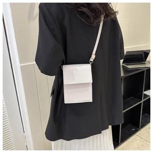 Minimalist cream white crossbody phone bag shown on a model with a black blazer