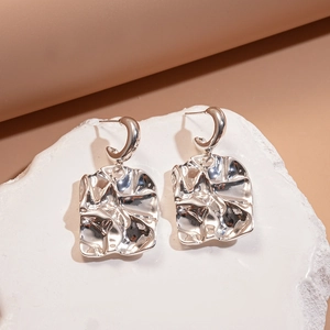 Close-up of silver pleated square earrings with irregular wave design and metallic luster