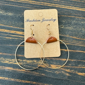 Detail of gold metal hoop earrings with brown leather accent on a jewelry card display