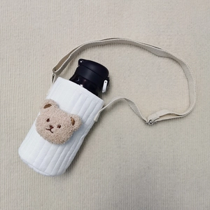 Detail of white quilted cup holder with cute brown bear patch and adjustable strap