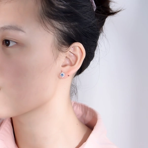 Elegant flower stud earrings with blue zircon and pearls shown on model's ear