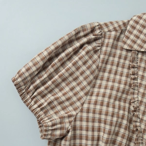 Detail of vintage plaid blouse showing ruffled edges and retro puff sleeve texture