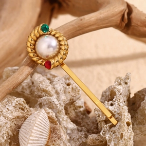 Detail of 18K gold twist hair clip featuring a large pearl and colorful gemstones