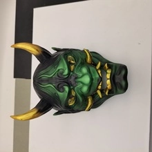 Detail of green and gold Japanese Oni mask decoration with sharp resin horns and teeth
