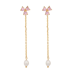 Close-up of gold tassel earrings with pink heart-shaped gems and white pearl pendants