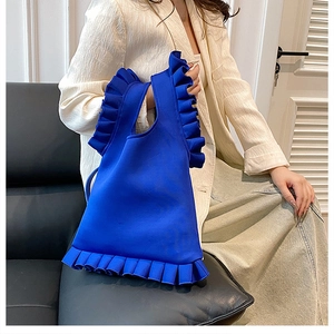 Close-up of klein blue pleated shoulder bag with chic ruffle trim and knitted fabric