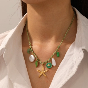 Detail of a woven green necklace with starfish, pearl, green gem, and bee pendants