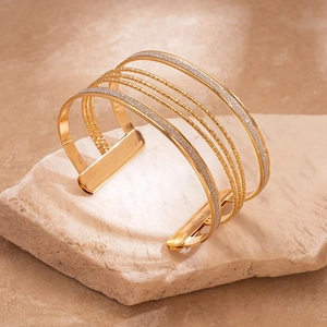Detail of gold multi-layer geometric cuff bracelet with glitter finish and textured bands