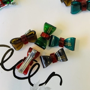 Dettaglio di fermagli per capelli a fiocco colorati con logo oro France Handmade e clip
