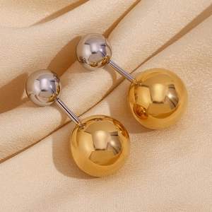 Detailansicht der zweifarbigen Doppel-Kugel-Ohrstecker in Gold und Silber auf Satin