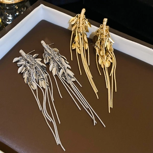 Detail of golden and silver metallic tassel earrings with leaf structure and long chains
