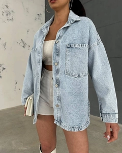 Detail view of washed light blue denim jacket with large pockets and metal buttons