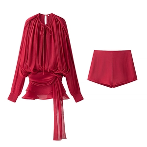 Detailed view of dark red puff sleeve blouse and pleated shorts with waist tie