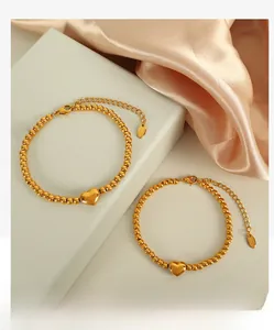 Détails d'un bracelet en perles dorées avec pendentif cœur et fermoir mousqueton réglable