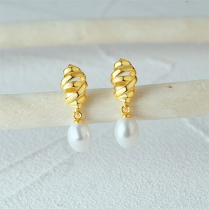 Macro view of gold croissant pearl drop earrings showing fine metal textures and luster